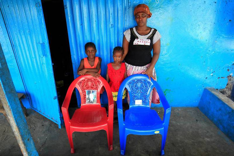 Mariama Bah and her children Kadijatu Jalloh, centre, and Binta Jalloh pose for a family portrait at their home in West Point, Monrovia, Liberia. The empty chairs symbolise Mariama’s late husband and son, Alhaji Cellou Jalloh and Alpha Umaru Jalloh, who died of the Ebola virus. Ahmed Jallanzo / EPA