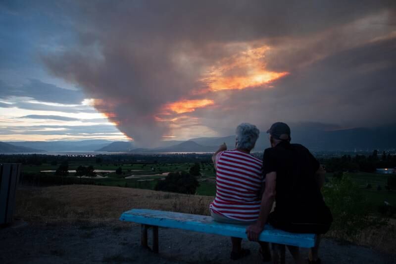 A couple view the newly ignited Mount Law wildfire, near Peachland and Glenrosa on the west side of Okanagan Lake, from the waterfront in Kelowna, British Columbia, Canada.