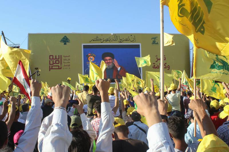 Supporters of the Lebanese Shiite militant movement Hezbollah wave th group's flag during a commemoration marking the 13th anniversary of the end of the 2006 war with Israel in the southern Lebanese town of Bint Jbeil on August 16, 2019. Hezbollah displayed a video showing a sample of its naval missiles, which was used 13 years prior to target an Israeli warship off the Lebanese coast during the July 2006 conflict. / AFP / Mahmoud ZAYYAT
