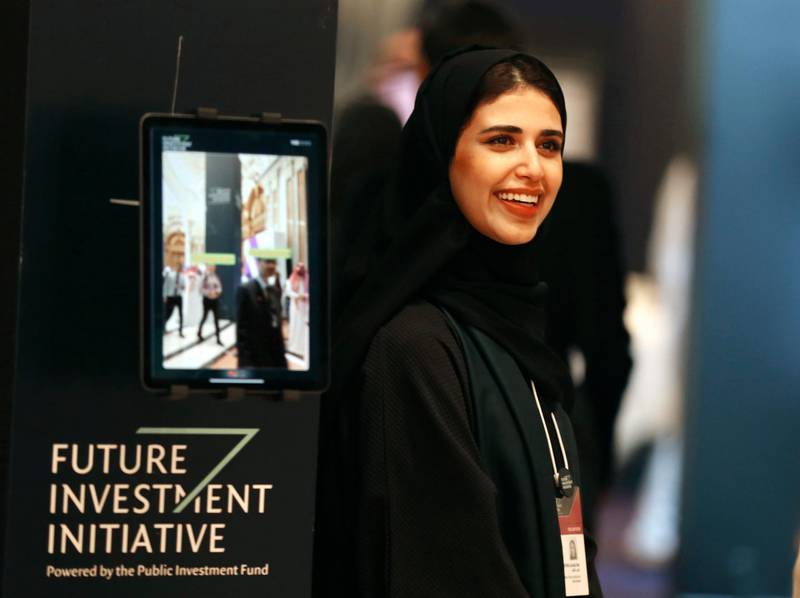 A Saudi organizer at the Future Investment Initiative forum smiles as she welcomes participants, in Riyadh, Saudi Arabia. AP Photo