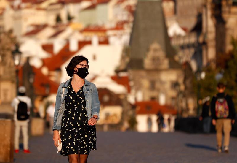 A young woman wearing a face mask walks across the medieval Charles Bridge in Prague, Czech Republic. AP Photo