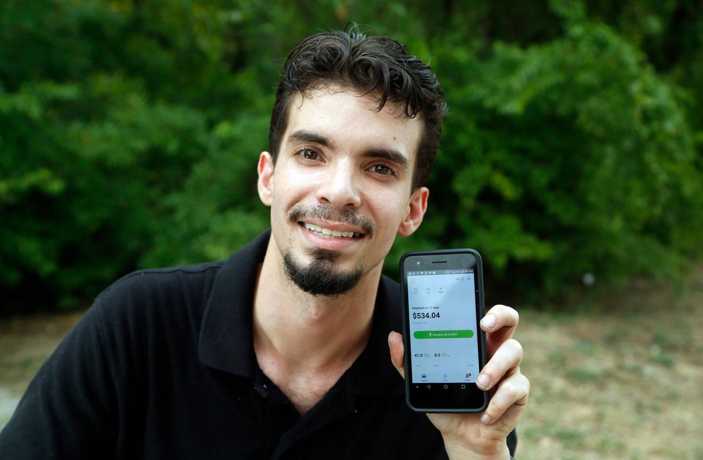 In this July 28, 2018, photo, Luis Vazquez, an overnight support manager at Walmart in Dallas, poses for a photo. He uses the Instapay app, developed by technology company Even, to assist him with his finances. The phone app allows users to access up to 50 percent of their earned wages during a pay period and avoid payday loans. (AP Photo/Michael Ainsworth)