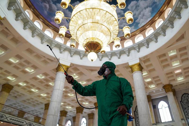 An employee wearing hazmat suit sprays disinfection liquid at the Golden Mosque in Jakarta, Indonesia. This will be the second straight year that Eid al-Fitr, the biggest and busiest Muslim holiday, has been muted, which could dampen growth outlooks in Indonesia. Bloomberg