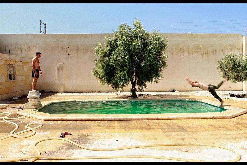 A Free Syrian Army fighter dives into a swimming pool, as his fellow fighter watches him in Aleppo, Syria. Hamid Khatib / Reuters