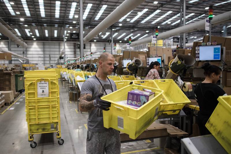 Employees pack boxes of merchandise at an Amazon.com Inc. fulfillment center in Peterborough, U.K., on Tuesday, Nov. 15, 2016. The online retail giant needs smart engineers to help expand its cloud computing division, automate warehouses and develop new gadgets like the voice activated Echo speaker. Photographer: Simon Dawson/Bloomberg