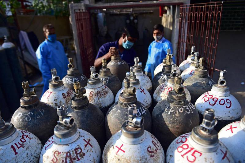 A health worker arranges oxygen cylinders that are being used for Covid-19 coronavirus patients at a private hospital in Allahabad. AFP