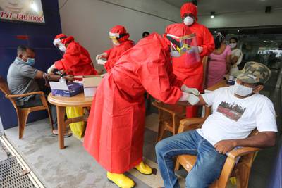 Sri Lankan health workers wearing protective equipment perform COVID-19 blood tests in Colombo. EPA