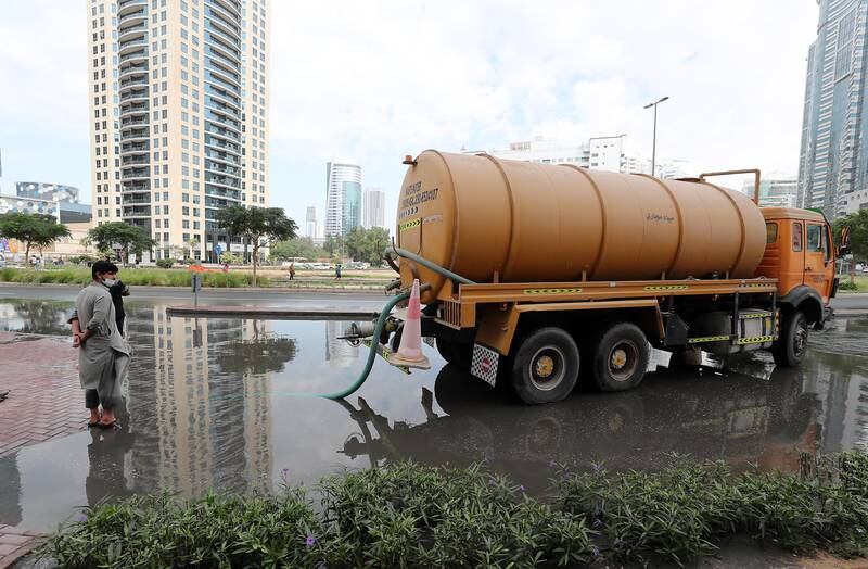 Workers clear a flooded road in Al Barsha heights. Pawan Singh / The National