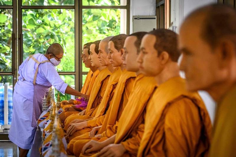 A Buddhist nun cleans wax figures of venerable monks displayed in a Buddhist temple outside Bangkok in Thailand. AFP