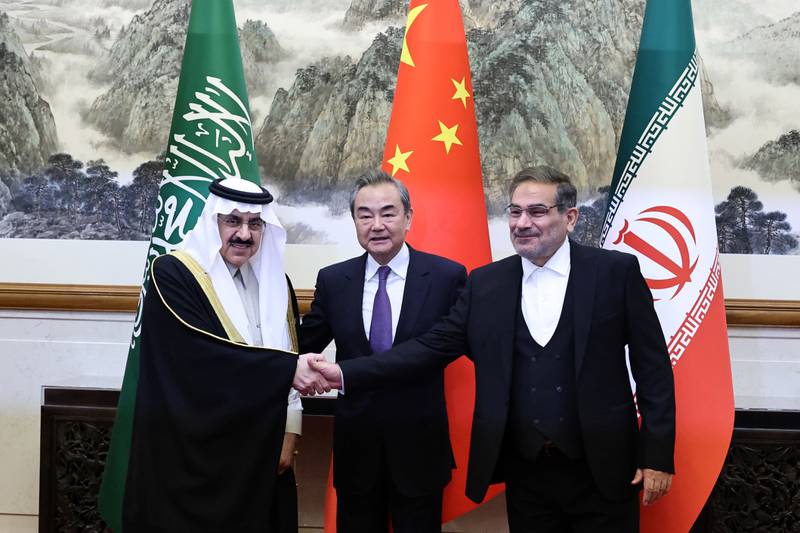 Ali Shamkhani, the secretary of Iran's Supreme National Security Council, right, shakes hands with Saudi national security adviser Musaad bin Mohammed Al Aiban, as Wang Yi, China's most senior diplomat, looks on, in Beijing, on March 11. Reuters