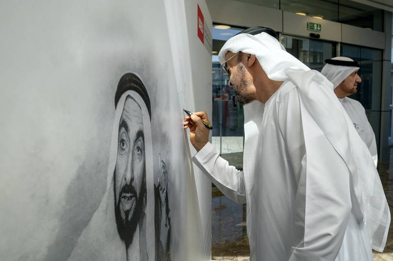 AL AIN, ABU DHABI, UNITED ARAB EMIRATES - February 07, 2019: HH Sheikh Mohamed bin Zayed Al Nahyan, Crown Prince of Abu Dhabi and Deputy Supreme Commander of the UAE Armed Forces (C), sings a portrait of HH Sheikh Zayed bin Sultan bin Zayed Al Nahyan, during a visit to the United Arab Emirates University. 
( Ryan Carter for the Ministry of Presidential Affairs )
---