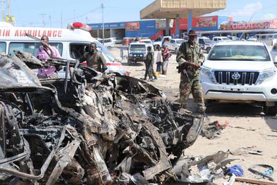 A soldier is seen next to the wreckage of car that was damaged during the car bomb that exploded in Mogadishu. AFP