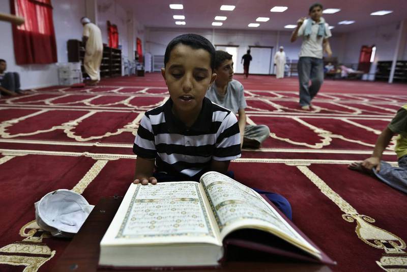 A Syrian refugee boy reads the Quran during Ramadan at the mosque in the Mrajeeb Al Fhood refugee camp, east of Zarqa, July 1, 2014. Muhammad Hamed / Reuters