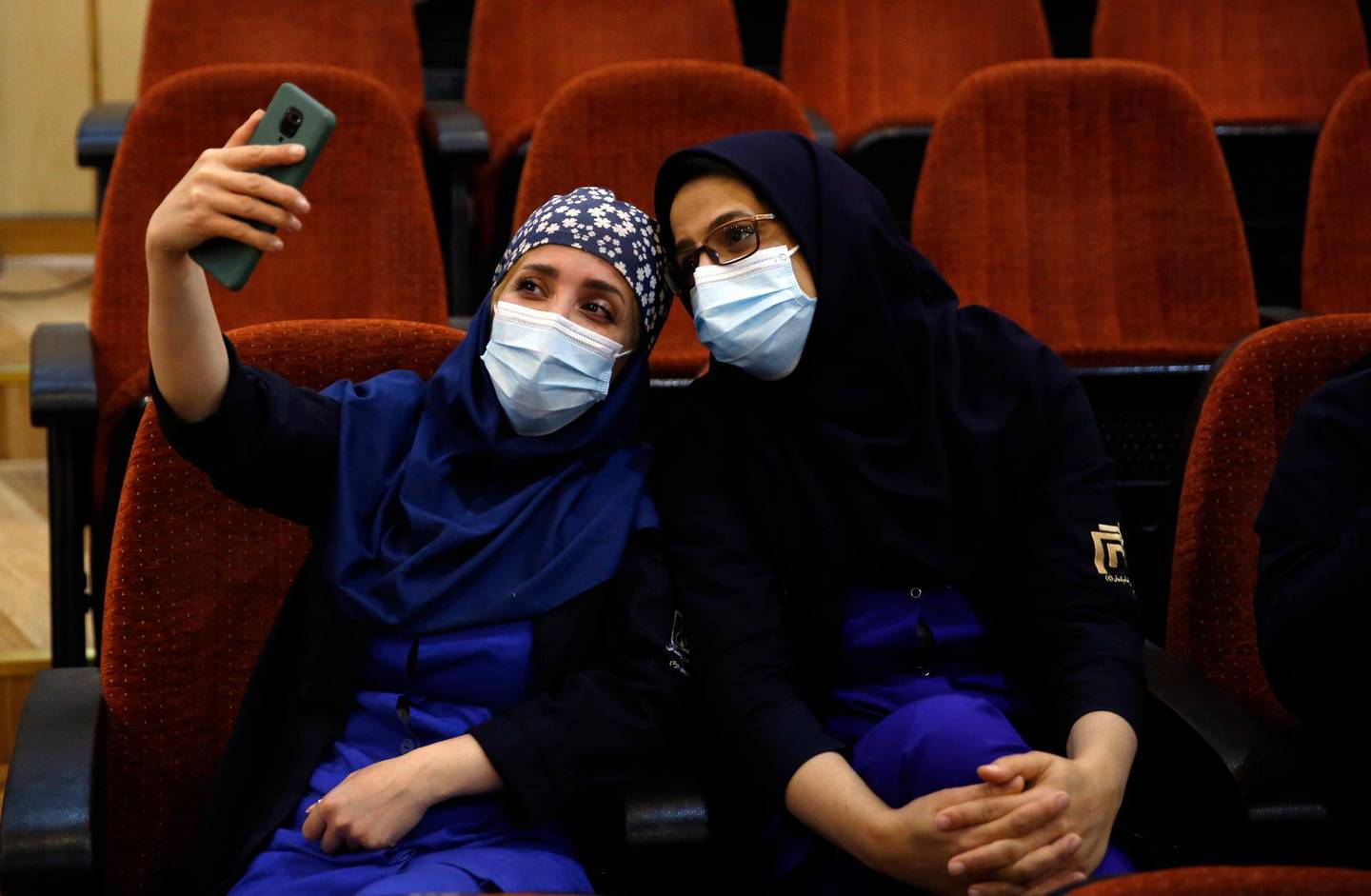 epa08998250 Iranian health workers take selfie before getting Sputnik V Covid-19 vaccine during a ceremony at the Imam Khomeini hospital in Tehran, Iran, 09 February 2021. Iran started its COVID-19 vaccination after receiving the first package of Russian Sputnik V vaccine.  EPA/ABEDIN TAHERKENAREH