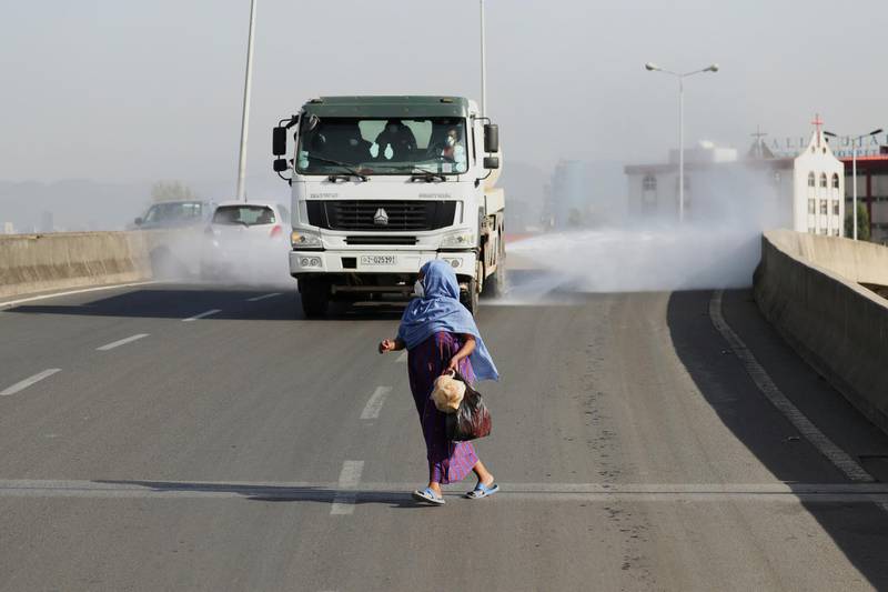 A woman wearing a face mask, runs in front of a truck spraying disinfectant on the street as part of measures to prevent the potential spread of coronavirus (COVID-19), in Addis Ababa, Ethiopia. REUTERS