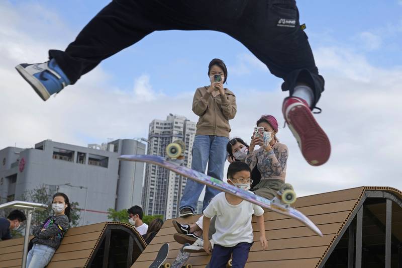 Children wearing masks watch a teenager flipping his skateboard in an 'ollie' at a park in Hong Kong. AP Photo