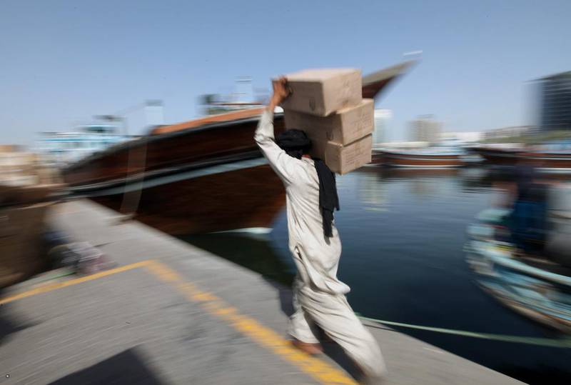 A worker carries goods to transport to traditional dhows at Al-Khor in the Dubai Creek area. Ali Haider / EPA