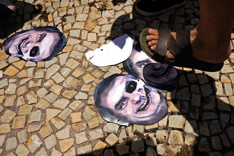 Demonstrators stomp on masks depicting Brazilian President Jair Bolsonaro as they protest his government's handling of the Covid-19 pandemic in Brasilia. AP