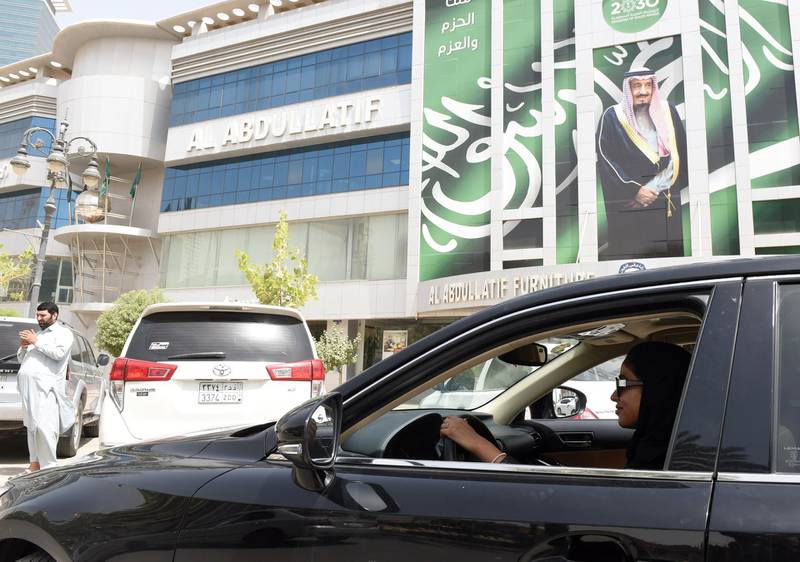 Saudi Majdoleen Mohammed Alateeq, a newly-licensed Saudi driver, drives her car drives her car next to a poster of theSaudi king Salman bin Abdulaziz in the Saudi capital Riyadh, on June 24, 2018. - Saudi Arabia ended its longstanding ban on women driving on June 24, 2018 -- and the second the clock struck midnight, women across the country started their engines. (Photo by Fayez Nureldine / AFP)
