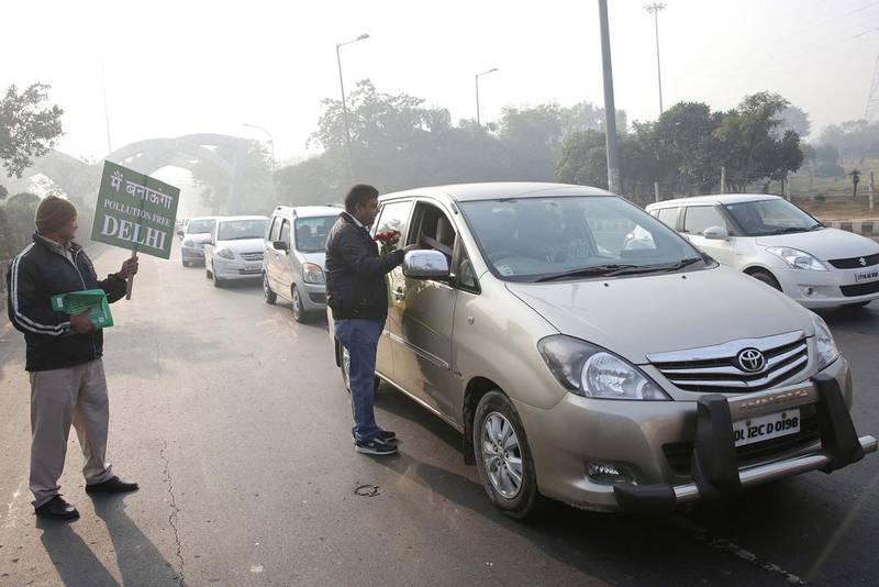 Indian civil defence volunteers distribute roses and urge commuters not to drive an even numbered licence plate car during the first day of the implementation of the odd-even scheme for vehicles in New Delhi on January 1. EPA