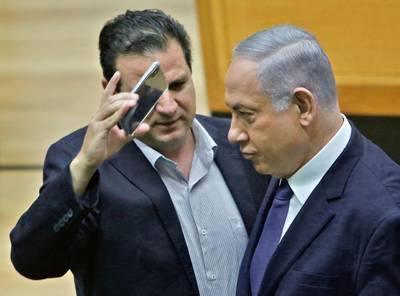 Israeli-Arab Knesset member Ayman Odeh (L) uses a phone to take a close-up picture of Prime Minister Benjamin Netanyahu in the main Knesset chamber in Jerusalem on September 11, 2019. A rare clash erupted between Netanyahu and Joint List Chairman Odeh on September 11 at the Knesset during a discussion ahead of a vote on a controversial, Likud party-sponspored bill to allow cameras in polling booths. / AFP / Gil COHEN-MAGEN
