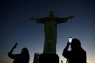 People take photos as the Christ the Redeemer statue is seen with the message "Vaccine Saves" projected, to make the population aware of the importance of the coronavirus disease vaccine, promoted by the United Vaccine Movement, in Rio de Janeiro. Reuters