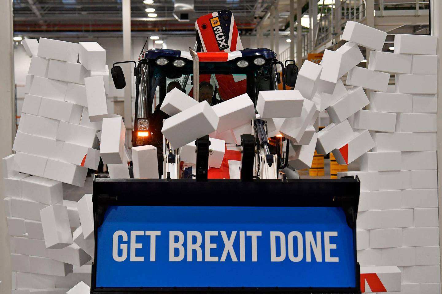 FILE - In this Tuesday Dec. 10, 2019 file photo, Britain's Prime Minister Boris Johnson drives a JCB through a symbolic wall with the Conservative Party slogan 'Get Brexit Done' in the digger bucket, during an election campaign event at the JCB manufacturing facility in Uttoxeter, England. Johnson's Conservatives won an overwhelming majority in the election two days later and Britain is now scheduled to leave the European Union on Jan. 31, 2020. (Ben Stansall/Pool via AP)