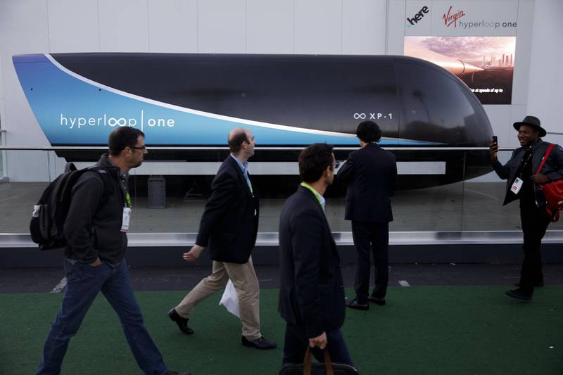 Attendees walk past a Virgin Hyperloop One XP-1 pod outside at the 2018 Consumer Electronics Show (CES) in Las Vegas, Nevada, U.S., on Thursday, Jan. 11, 2018. Electric and driverless cars will remain a big part of this year's CES, as makers of high-tech cameras, batteries, and AI software vie to climb into automakers' dashboards. Photographer: Patrick T. Fallon/Bloomberg