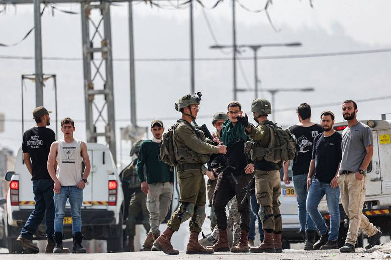 Israeli soldiers speak with settlers in the town of Huwara near Nablus in the occupied West Bank on Monday. AFP