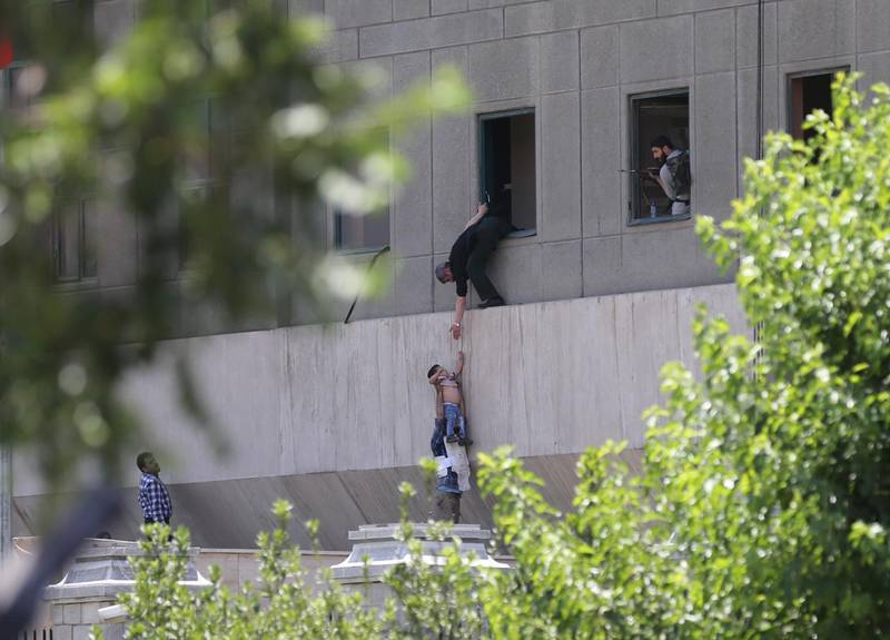 TEHRAN, IRAN - JUNE 7:  A police officer dangles a child from the window as the police conduct an operation against the attacker in the parliament building after gunmen opened fire at Irans parliament and the shrine of Ayatollah Khomeini in the capital Tehran, Iran on June 7, 2017. (Photo by Omid Vahabzadeh/Anadolu Agency/Getty Images)