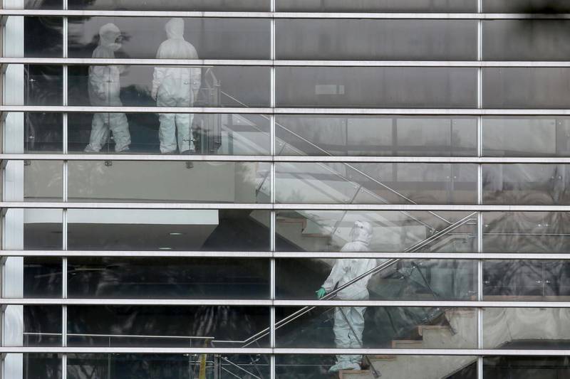 People wearing protective suits are seen at the windows of a sports centre where Colombian citizens have been isolated after being repatriated by the Colombian government from the Chinese city of Wuhan, the epicentre of the novel coronavirus outbreak, in Bogota, Colombia. Reuters