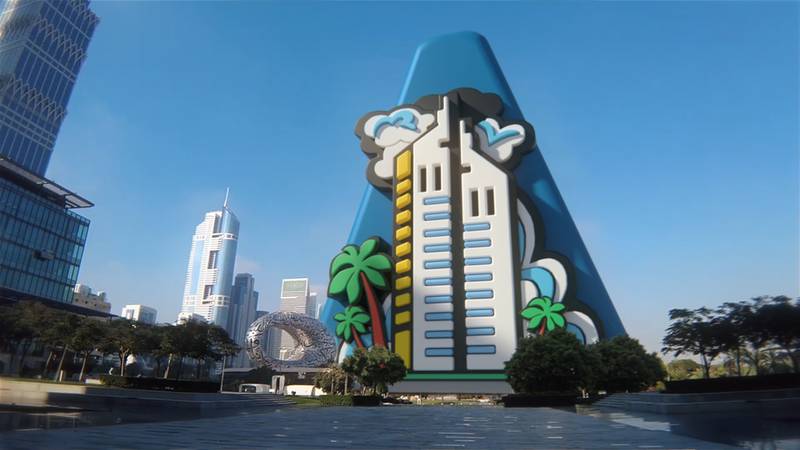 'A' stands behind a 3D render of Emirates Towers.