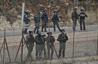 Israeli security forces stand behind a wire fence as Palestinians demonstrate in the northern West Bank city of Tulkarem following the funeral of 19-year-old Badr Nafla in the same city.  AFP