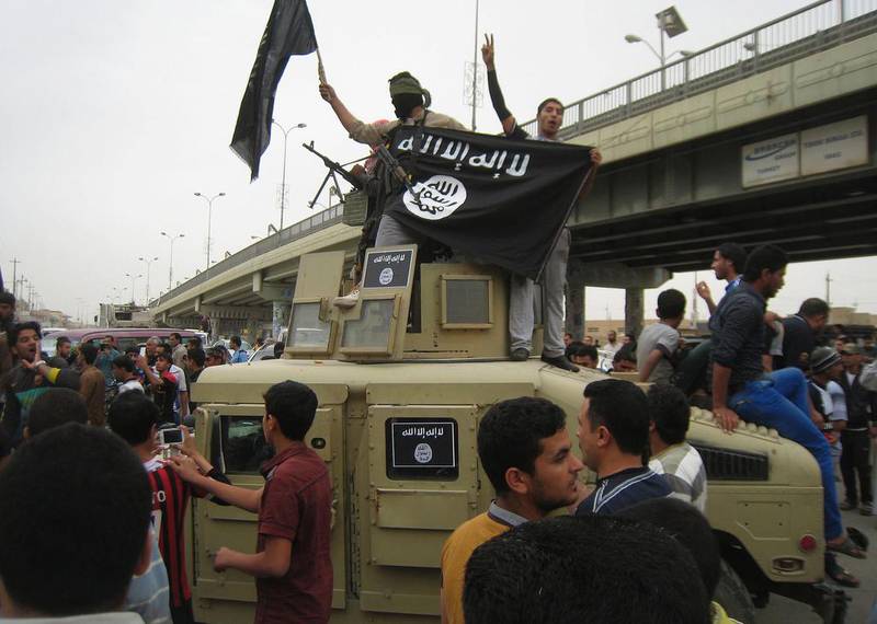 ISIL militants hold up their flag as they patrol in a commandeered Iraqi military vehicle in Fallujah, Iraq. AP Photo