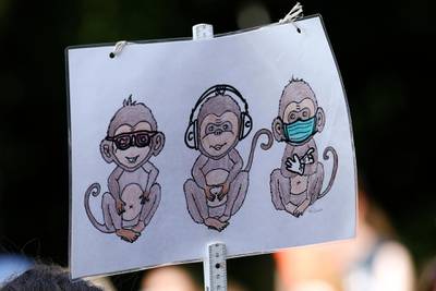 A placard displays the three wise monkeys pictorial maxim with a sanitary mask during a protest against coronavirus pandemic regulations in Berlin, Germany.  EPA