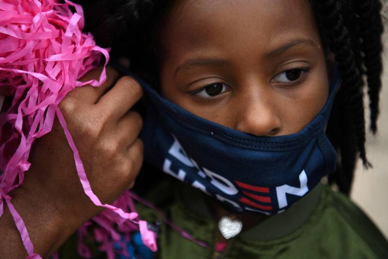 Pricillica McNulty, 6, receives help putting on a mask at an event encouraging community members to vote in the upcoming presidential election at an early voting site in Houston, Texas,.  Reuters