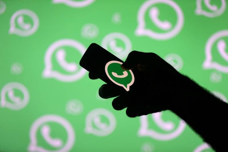 FILE PHOTO: A man poses with a smartphone in front of displayed Whatsapp logo in this illustration picture September 14, 2017. REUTERS/Dado Ruvic/File Photo