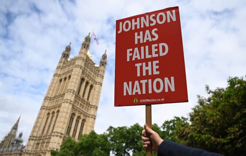 A protester holds up an anti-Boris Johnson placard outside parliament in London. EPA