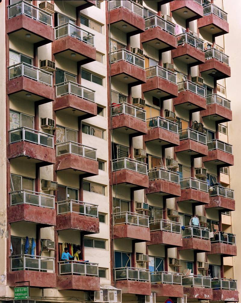 A 1980s apartment building with its evenly spaced balconies in a worn-down shade of red. Photo by Andrew Moore