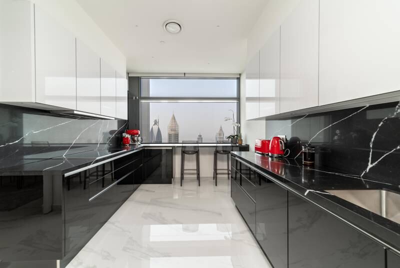 The kitchen is finished with sleek black and white fittings and bold red appliances