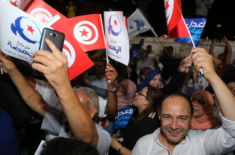 Suppoters of the Tunisian Islamist-inspired Ennahdha party celebrate in reaction to the first exit polls in front of the party's office in the capital Tunis on October 6, 2019.  Exit polls showed Ennahda party leading that of a jailed business tycoon in Tunisia's legislative polls, weeks after a presidential election that reshaped the country's post-Arab Spring political landscape. / AFP / ANIS MILI
