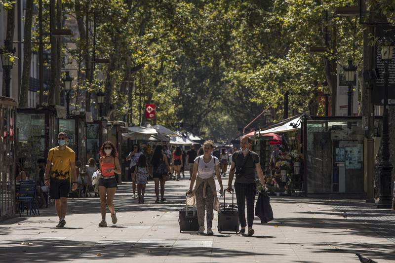 Tourists wheel luggage down Las Ramblas in Barcelona, Spain, on Saturday, Aug. 1, 2020. Spain’s economy suffered a bigger blow than expected in the second quarter, leaving it with a long recovery that’s become even tougher after a new hit to its vital tourism industry. Photographer: Guillem Sartorio/Bloomberg