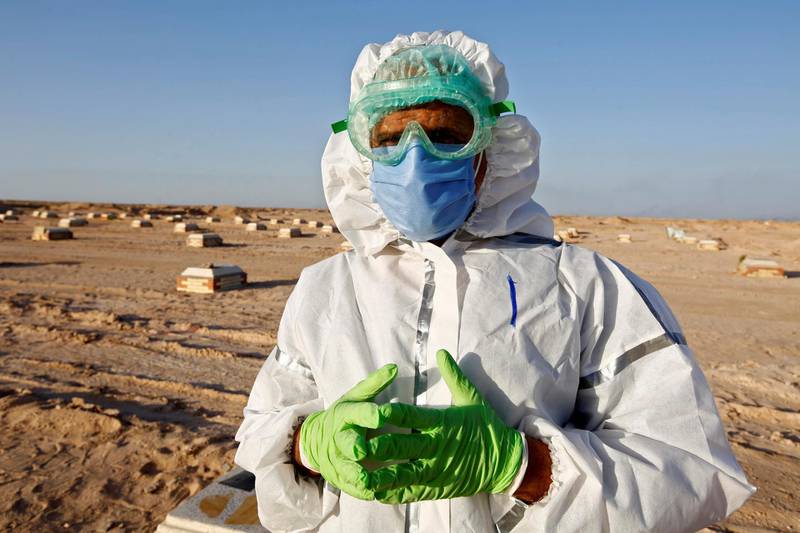 Abdelhussan Kadhim, from the PMF, who volunteered to work in the cemetery, wearing a protective suit and poses for the camera at the new Wadi Al Salam cemetery for those who died of the coronavirus. Reuters