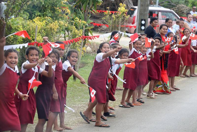 Tongan school children wave flags along the procession. Getty Images