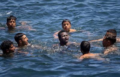 Migrants attempt to help one of their number in difficulty in the water at the border between Morocco and the Spanish enclave of Ceuta. AFP