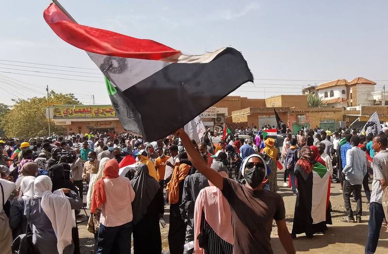 A Sudanese demonstrator waves a national flag during a protest against the October 2021 military coup, in the capital Khartoum, on January 13, 2022.  The demonstrations which converged from several parts of Khartoum came only days after the United Nations launched a bid to facilitate talks between Sudanese factions.  AFP