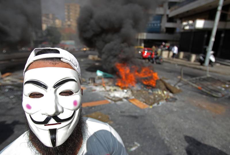 A protester wearing a Guy Fawkes mask looks in Beirut's Salim Slem neighbourhood. AFP