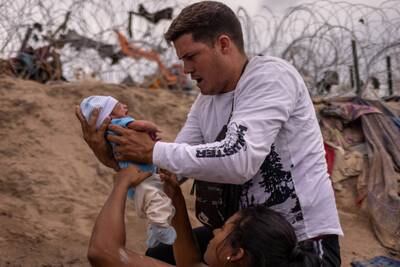 Yusniel, a migrant from Cuba, carries his 10-day-old son, Yireht, up the bank of the Rio Grande in Texas, US. Reuters
