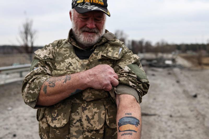 US war veteran Steven Straub shows his tattoo of the Ukrainian flag while on patrol near Buda-Babynetska, north of Kyiv, days after Russian forces retreated from the area. AFP