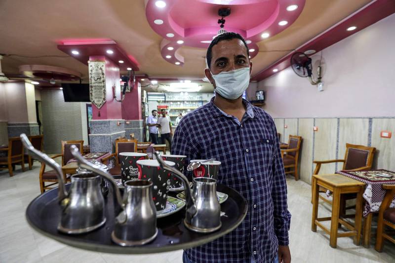 A waiter carries an order at a cafe in the Egyptian capital Cairo after authorities relaxed the lockdown measures in place to curb the spread of coronavirus. AFP